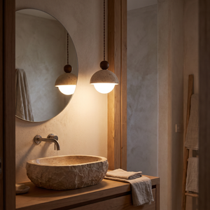Mira Travertine & Glass Pendant glowing with warm light in the evening